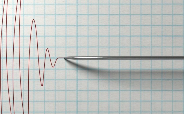 A closeup of a polygraph lie detector test needledrawing a red line on graph paper on an isolated white background