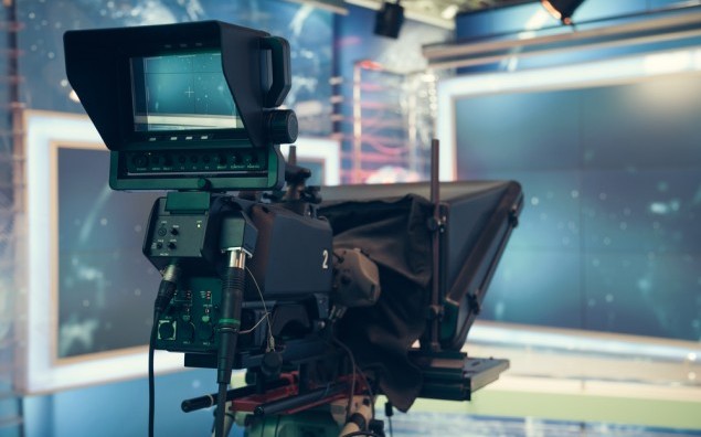 Television studio with camera and lights - recording TV NEWS. Shallow depth of field - focus on camera.