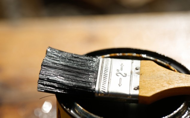 Brush resting on a tin can of protective paint for wood treatment against weathering, insects and fungus. Outdoor protection, carpentry, hard at work, home improvement, do-it-yourself concept.