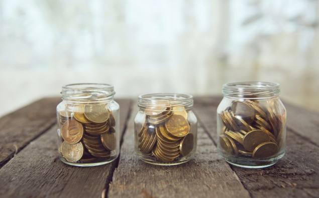 Glass jars with money coins ruble on wooden table. Cross Processing tone colored.