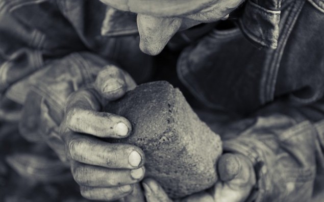 A loaf of bread in an old mans hands
