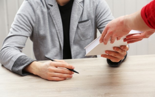 Author signing autograph in own book at wooden table on white planks background