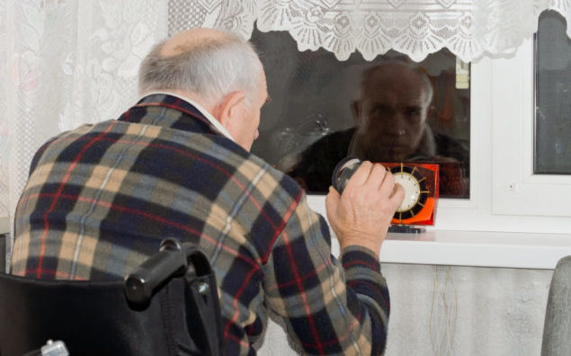 Handicapped man waiting at a window at night