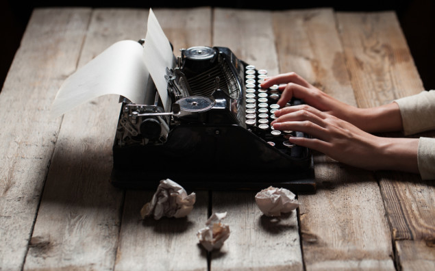 Hands writing on old typewriter over wooden table background