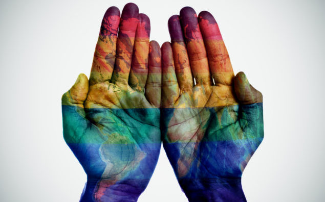 world map and rainbow flag in the hands
