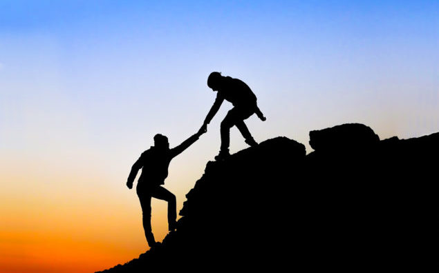 Silhouette of helping hand between two climber