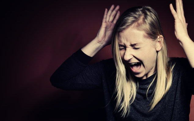 Blonde woman with hands in the air screaming in panic
